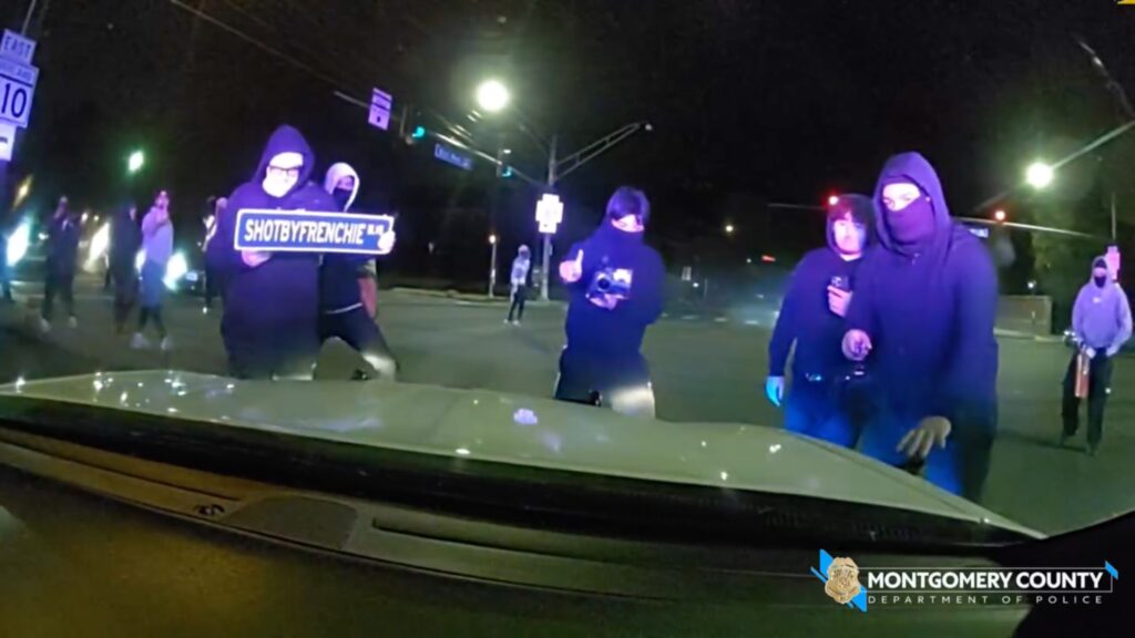Masked mob attacks police cruiser with officer inside during illegal street takeover